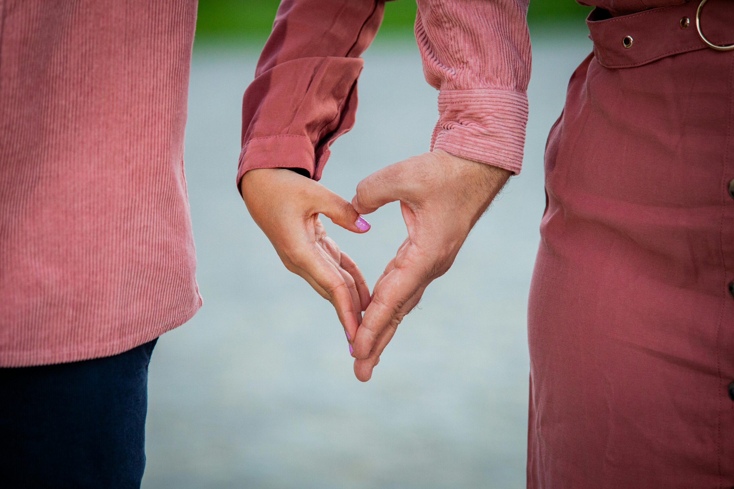 Two building make the love heart symbol with their hands, representing trust, connection and support through Gottman relationship counselling.