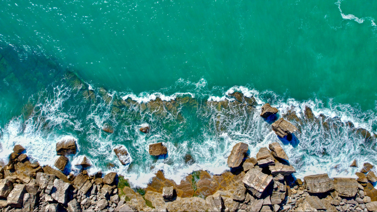 Aerial view of ocean waves and rocks, representing calm, perspective and emotional support through counselling in Darwin.